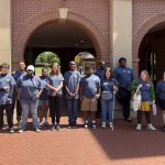 Students participating in the 2026 Summer Enrichment Academy pose in front of Luckyday Hall wearing their 50th Anniversary IDS tee shirts.
