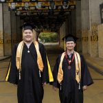RISE graduates Taylor Carley, left, and Dan Lewis, right, pose in their cap and gown at the Eagle Walk on campus.
