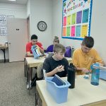 4 WINGS program participants sitting in the classroom working on skills.