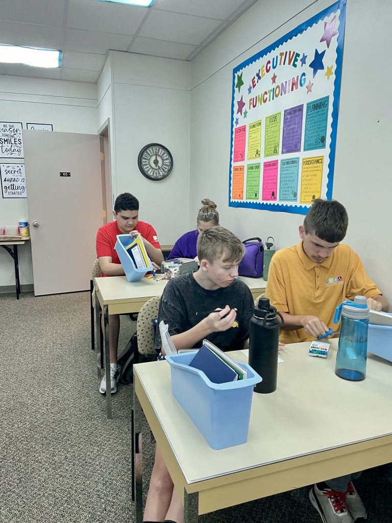 4 WINGS program participants sitting in the classroom working on skills.